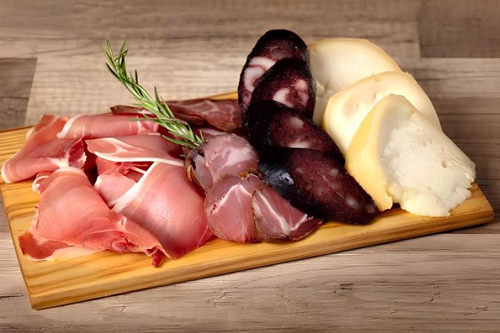 Charcuterie board with assorted meats, cheeses, and a rosemary sprig.