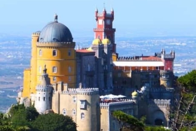 a castle with water in the background with Pena Palace in the background