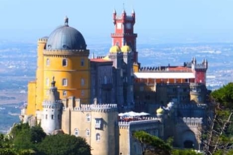 a castle with water in the background with Pena Palace in the background