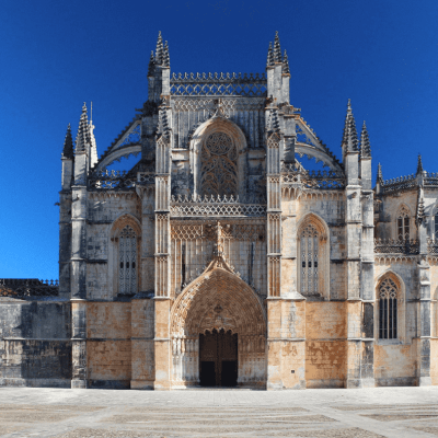 a large stone statue in front of a church with Batalha Monastery in the background