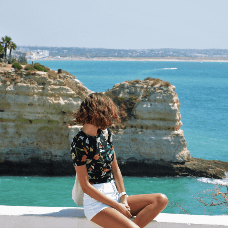 a person sitting on a rock next to a body of water