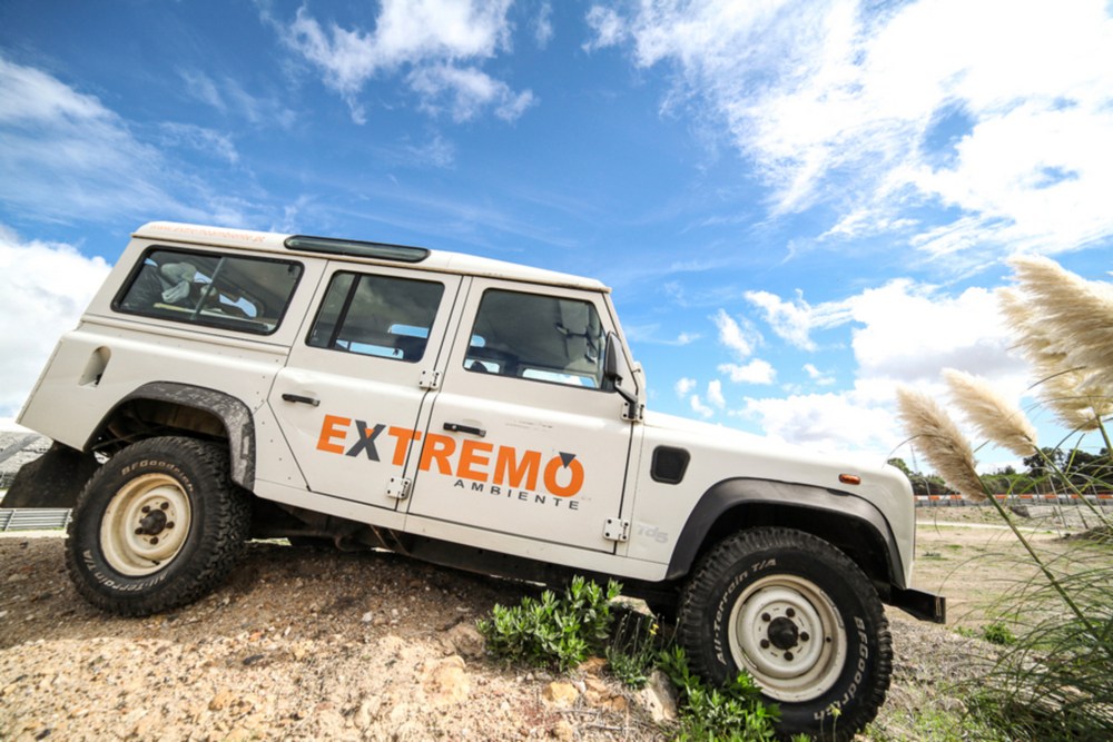 White off-road vehicle on rocky terrain under a blue sky with clouds.