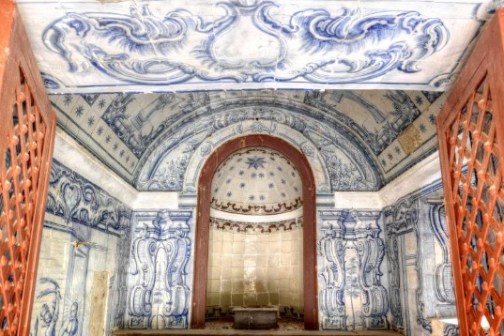 Intricately painted room with blue and white designs and red wooden lattice doors.