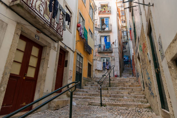 Narrow cobblestone alley with clothes hanging, colorful buildings, and steep stairs.