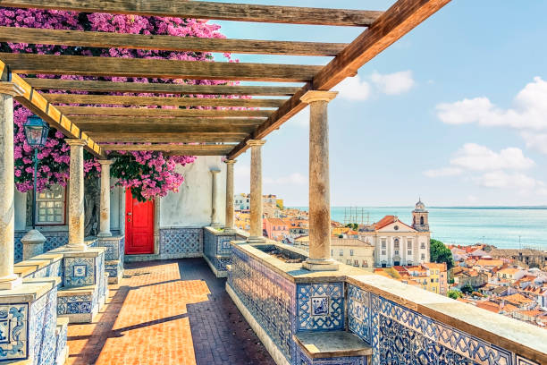 Pergola with purple bougainvillea, tiled walls, and a coastal city view with ocean in the background.