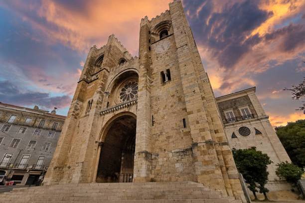Gothic cathedral with two towers at sunset, dramatic clouds in the sky.