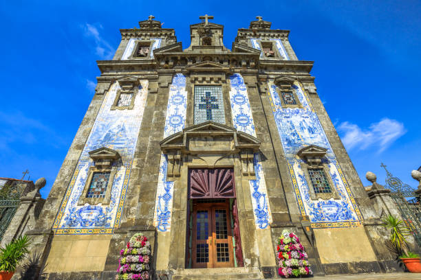 Historic church with ornate blue tile facade and decorative flowers, viewed from a low angle.